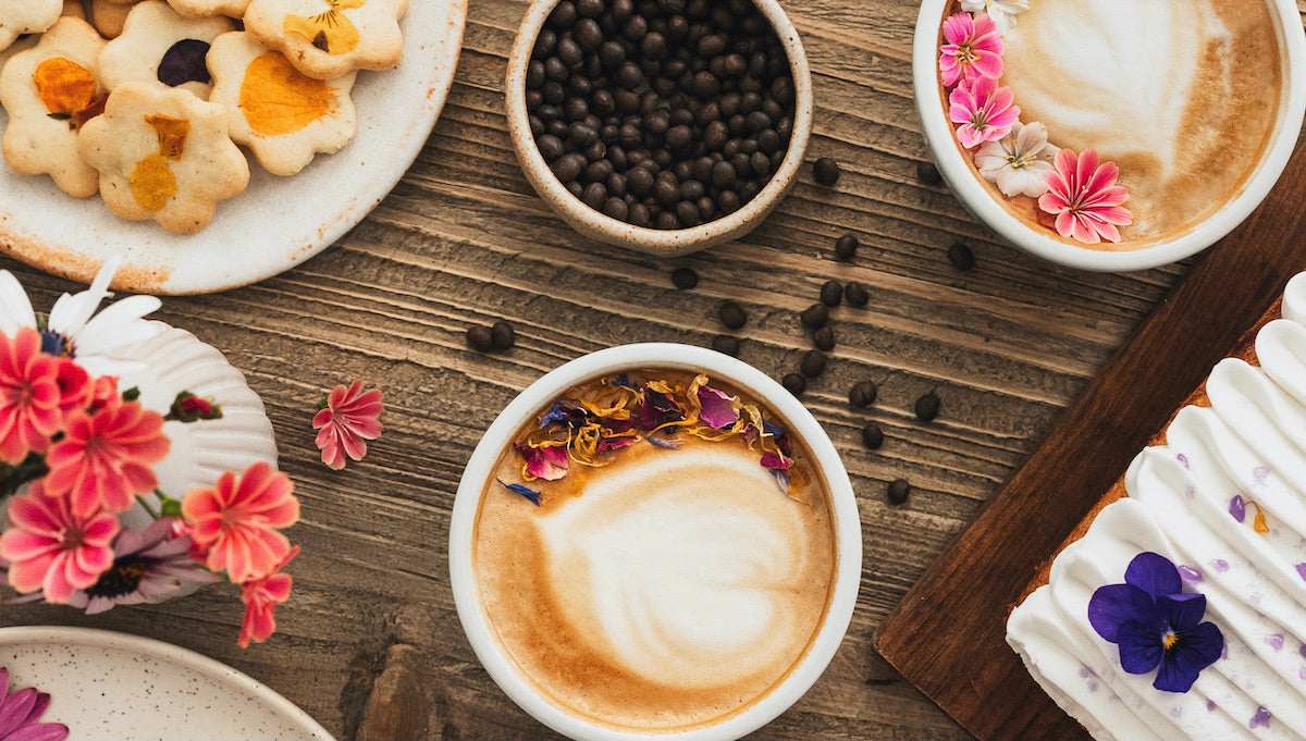Café de lupin avec mousse de lait entouré de diverses pâtisseries et des graines de café de lupin
