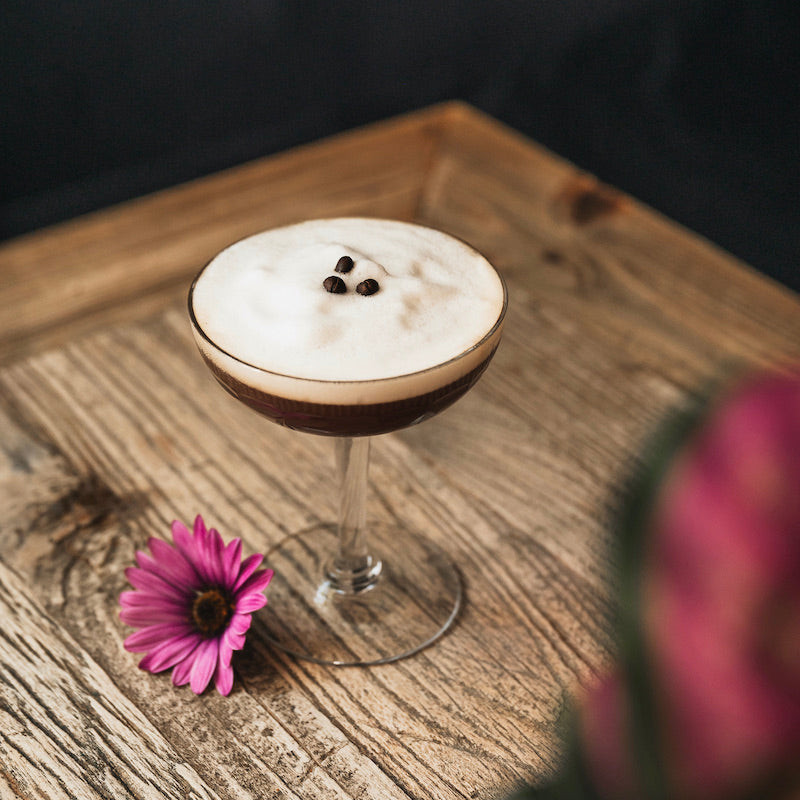 Un café de lupin avec de la mousse et 3 grains de café de lupin dans un verre à cocktail