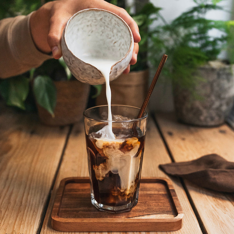 Un café de lupin froid avec une main qui verse du lait